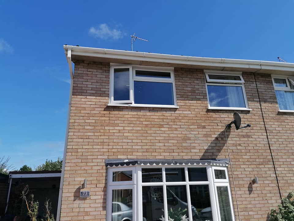 a brick house with white windows and a blue sky in the background .