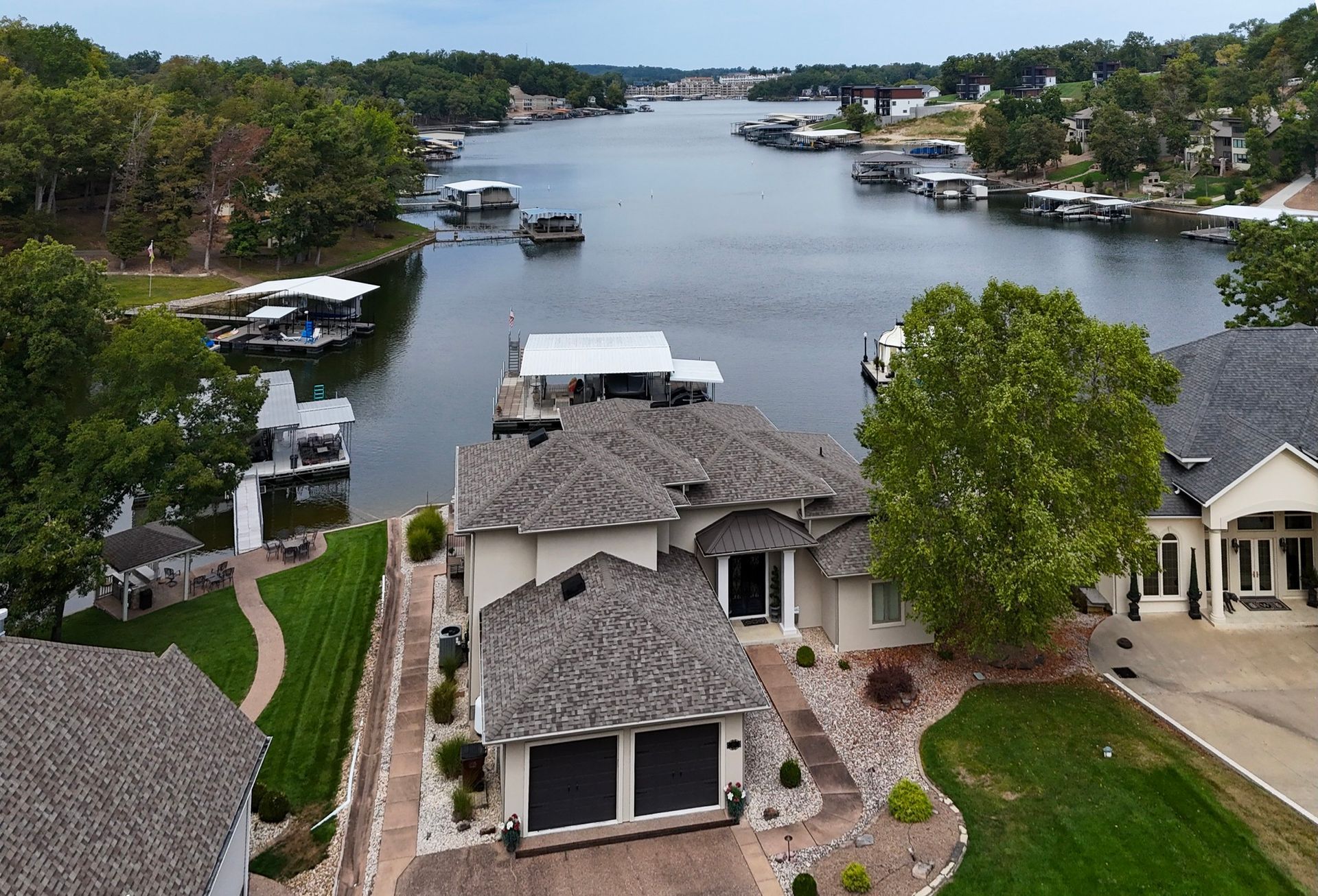 White house with dark roof, porch, trees and a bright blue sky.