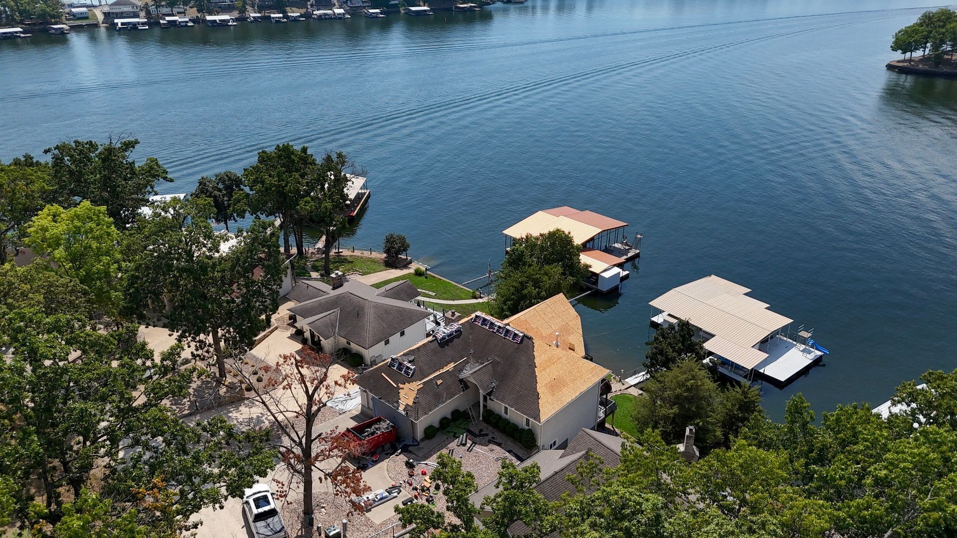 Houses along a lake with boat docks; blue water and green trees.