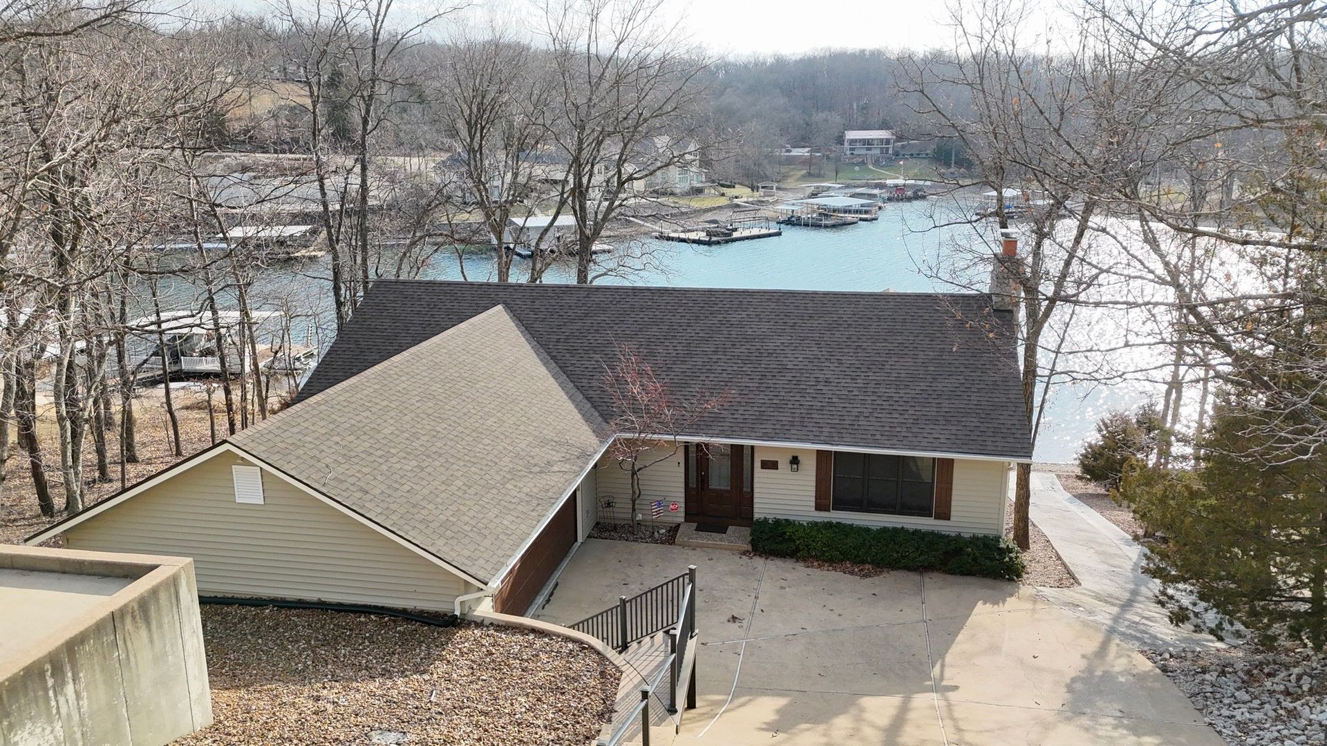 House with a brown roof and beige siding overlooking a lake with boats.