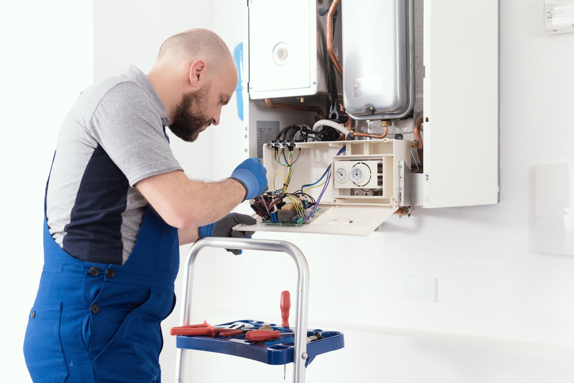 A man is working on a boiler in a kitchen.