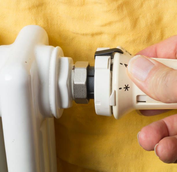 A person is adjusting a thermostat on a radiator.