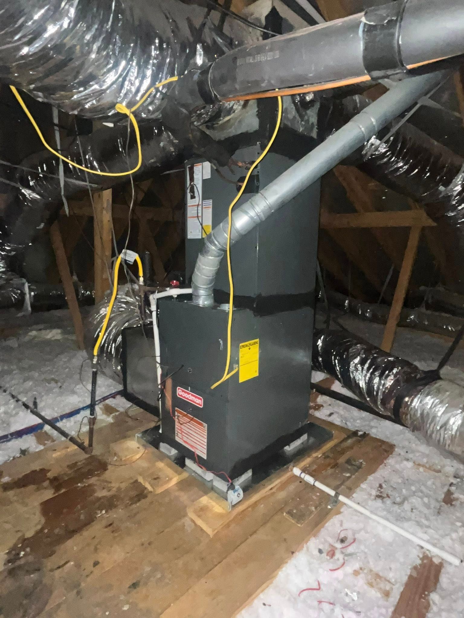 HVAC unit in an attic with ductwork, electrical wiring, and wood flooring.