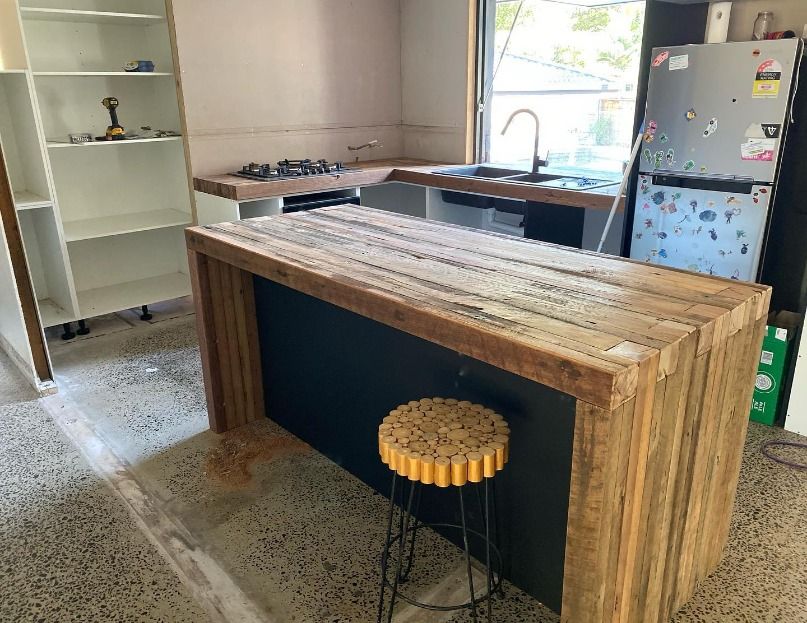 A Kitchen With A Wooden Island And A Stool — JC Coastal Construction In Coorabell, NSW