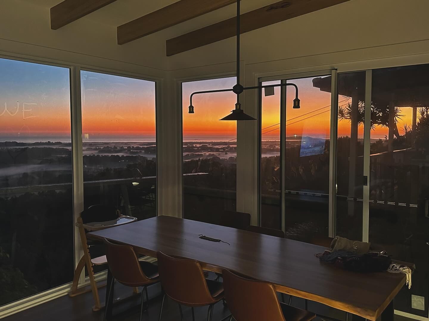 A Dining Room With A Table And Chairs And A View Of The Sunset — JC Coastal Construction In Coorabell, NSW