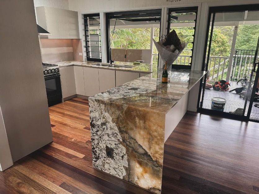 A Kitchen With A Large Granite Counter Top And Wooden Floors — JC Coastal Construction In Coorabell, NSW