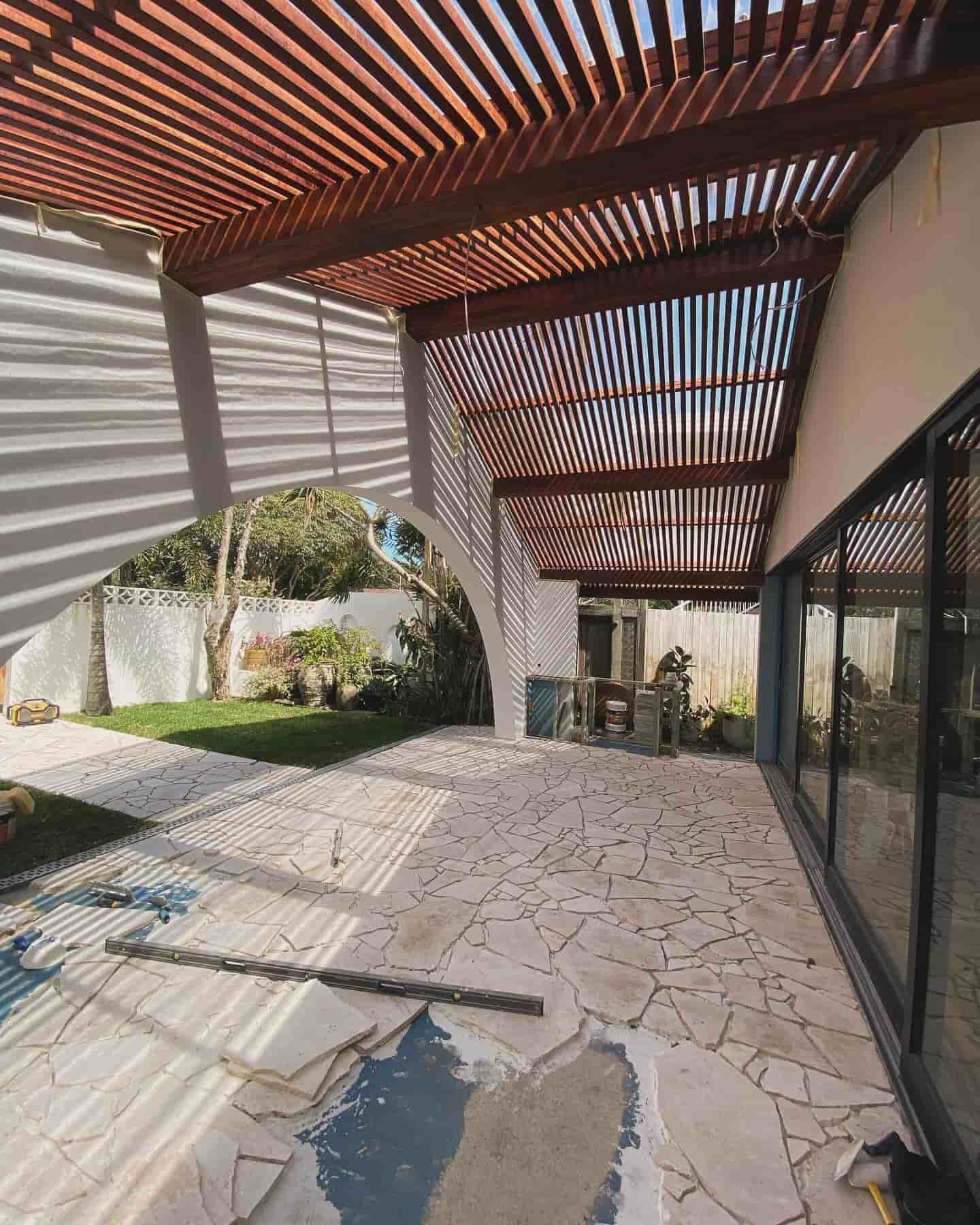 A Large Patio With A Wooden Pergola And Sliding Glass Doors — JC Coastal Construction In Coorabell, NSW