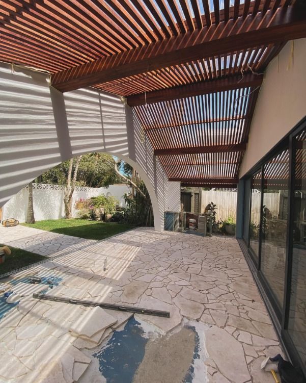 A Patio With A Wooden Pergola And Sliding Glass Doors — JC Coastal Construction In Coorabell, NSW