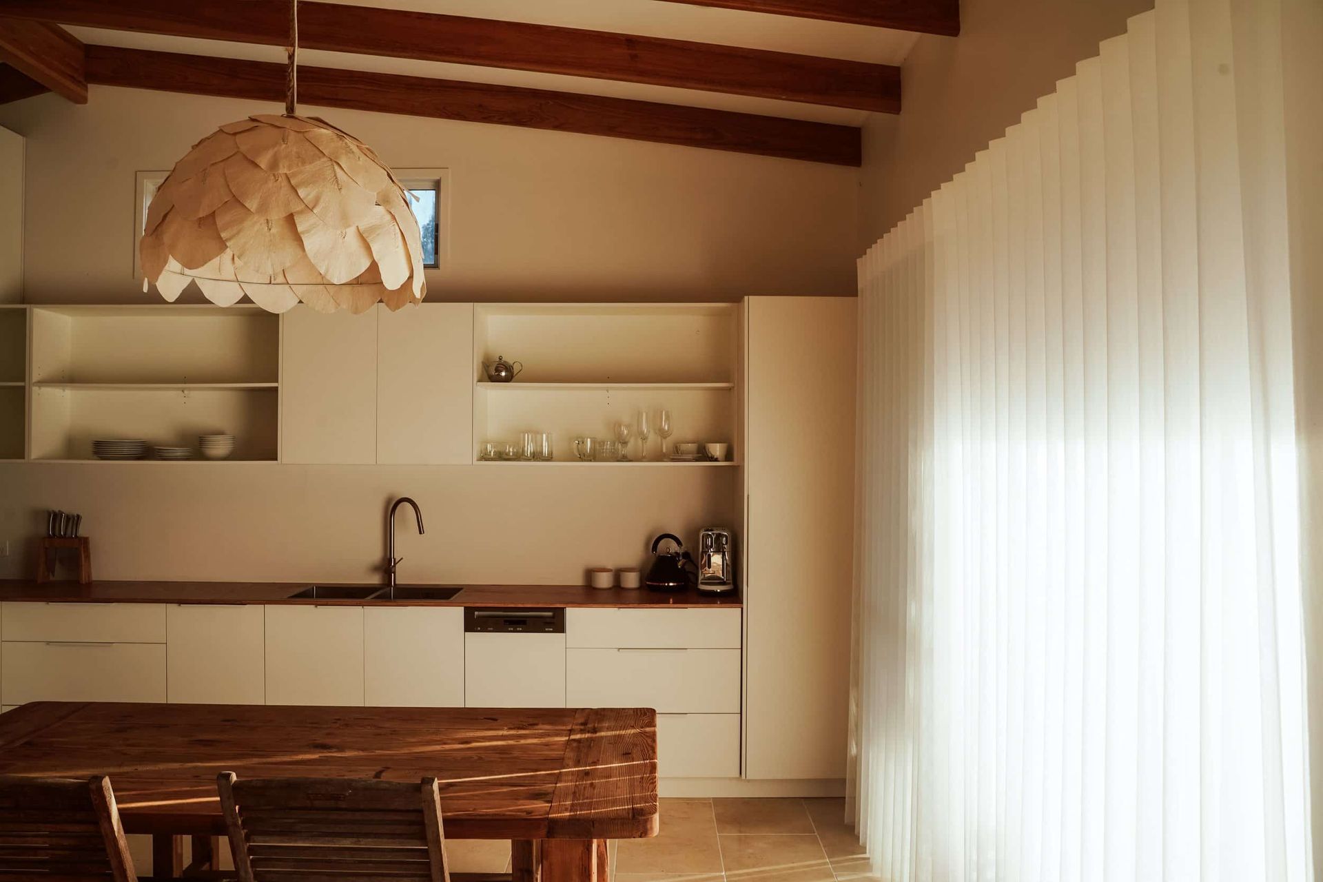 A Kitchen With White Cabinets And A Wooden Table And Chairs — JC Coastal Construction In Coorabell, NSW