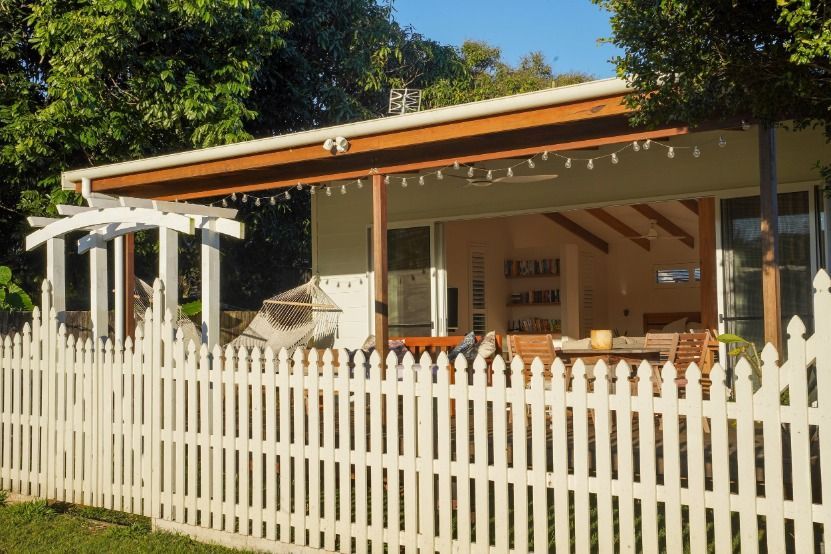 A White Picket Fence Surrounds A House With A Porch — JC Coastal Construction In Coorabell, NSW