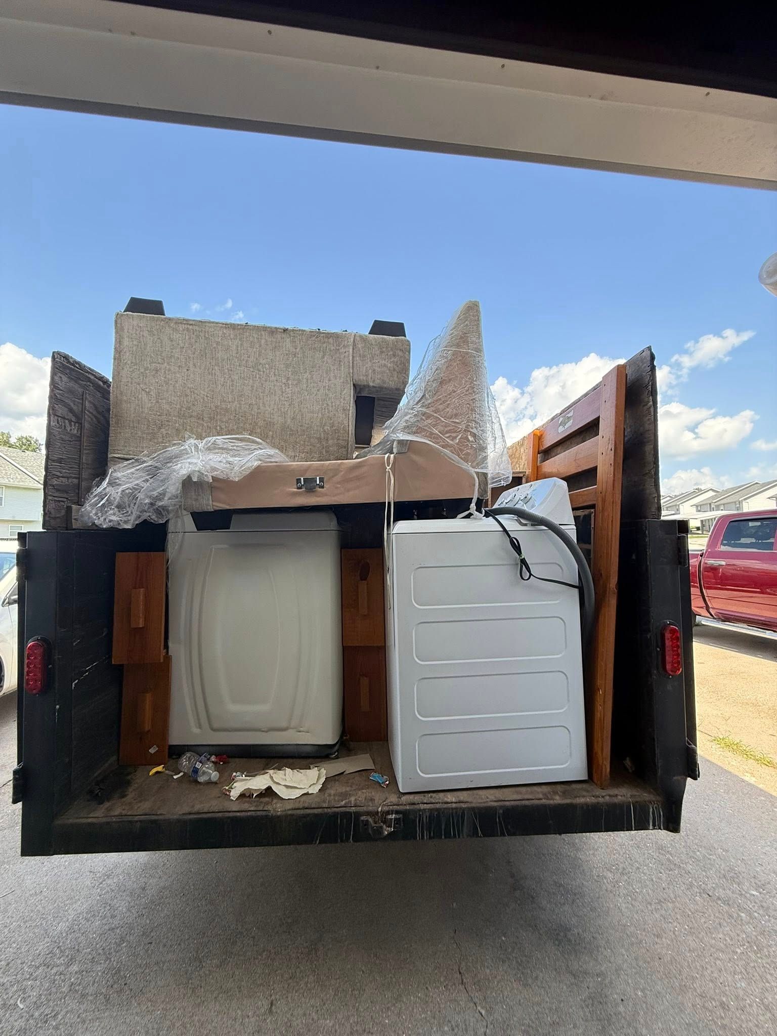 Pickup truck bed loaded with appliances and boxes, including a washer and dryer panel