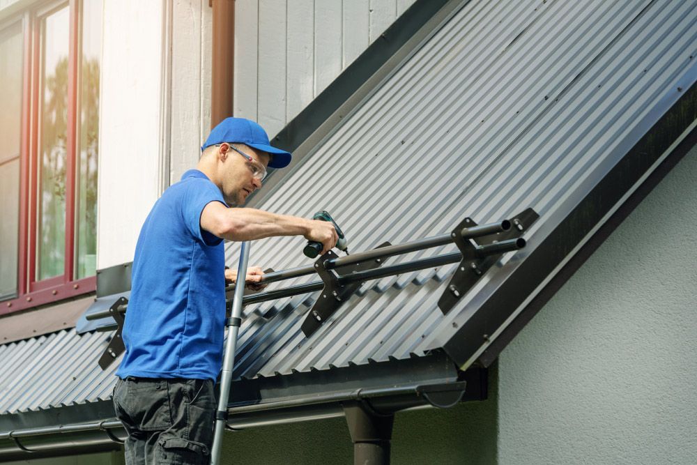Man Wearing Blue Cap Repairing The Metal Roof — Roofing In Byron Bay, NSW