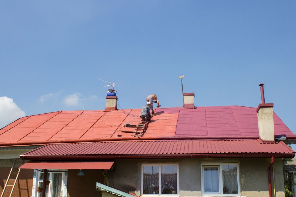 Two Men Painting Roof Red With Compressor — Roofing In Byron Bay, NSW