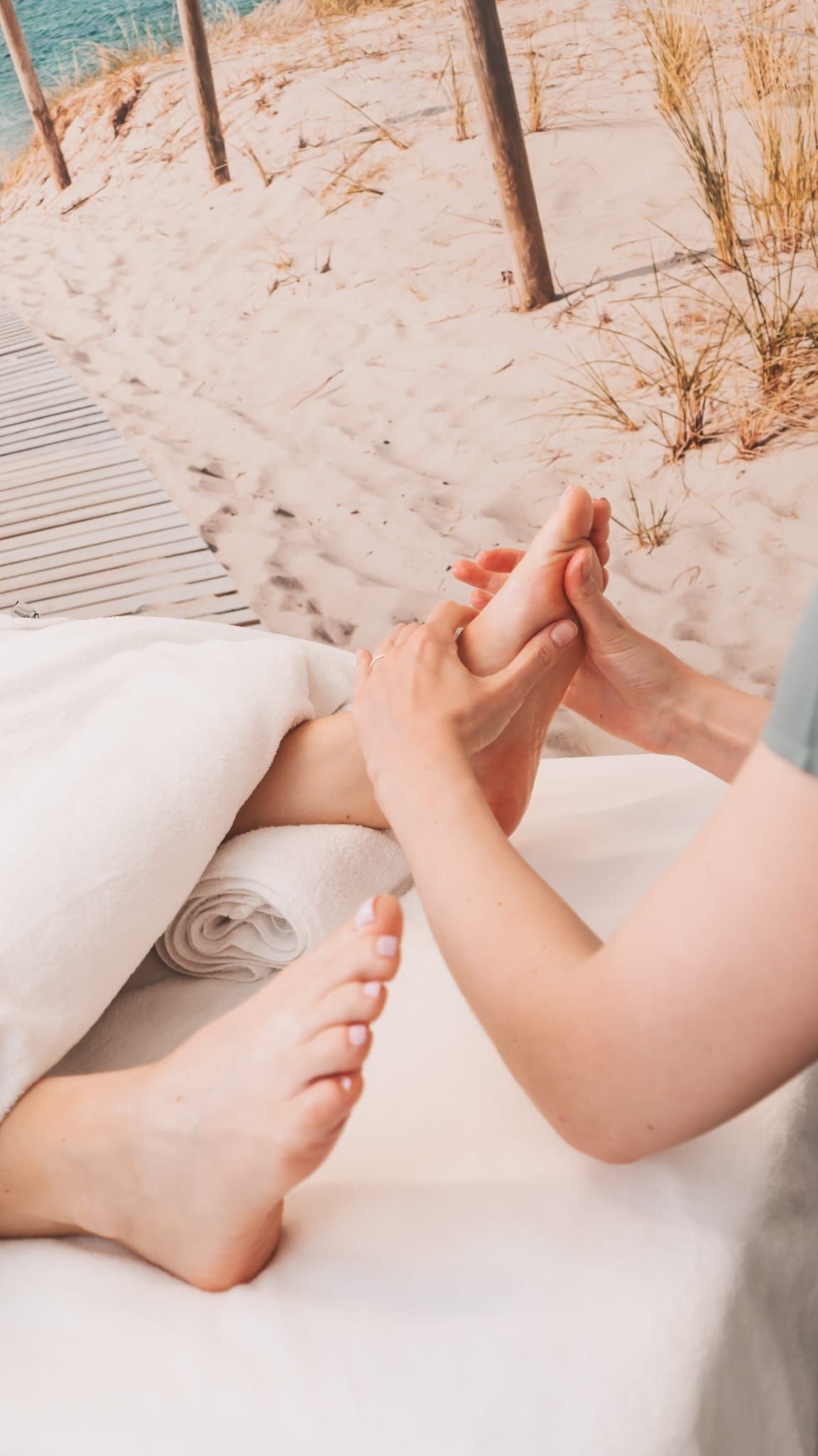 Person receiving a foot massage in a spa setting; therapist's hands on foot.