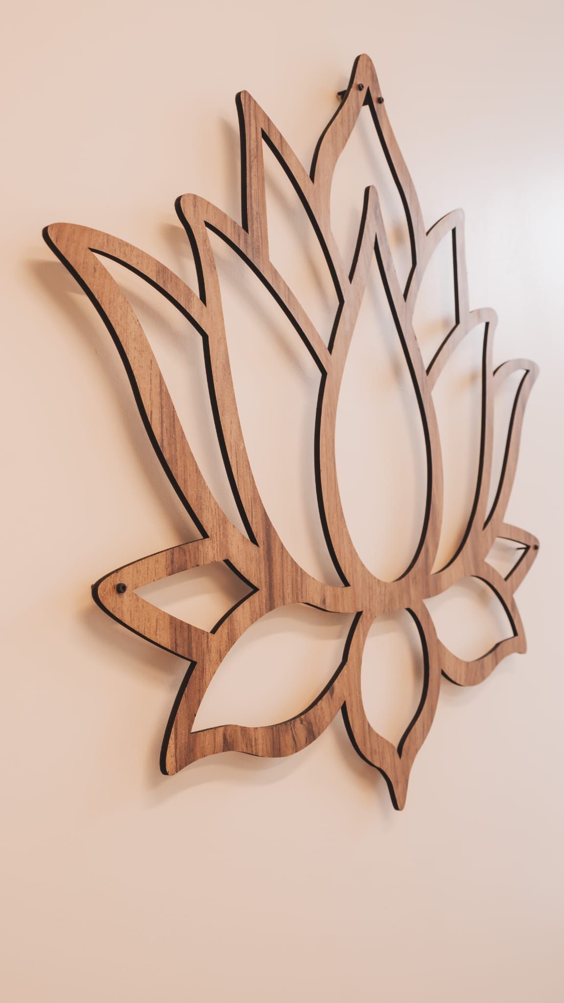 Wooden lotus flower wall art. Brown, open design with black outlines, mounted on a cream-colored wall.