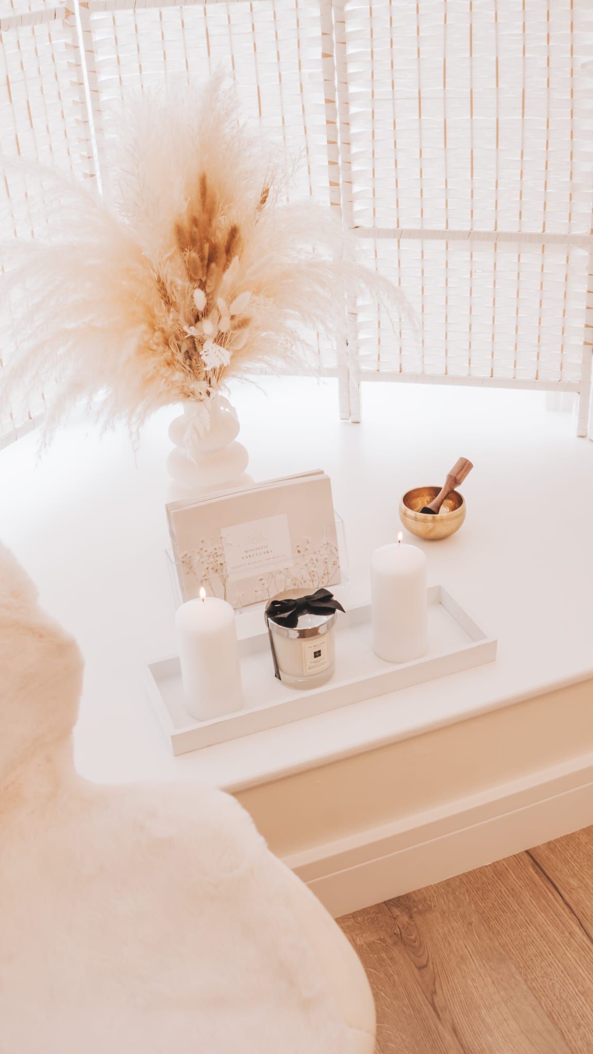 White table with decor: pampas grass, candles, tray, small bowl.