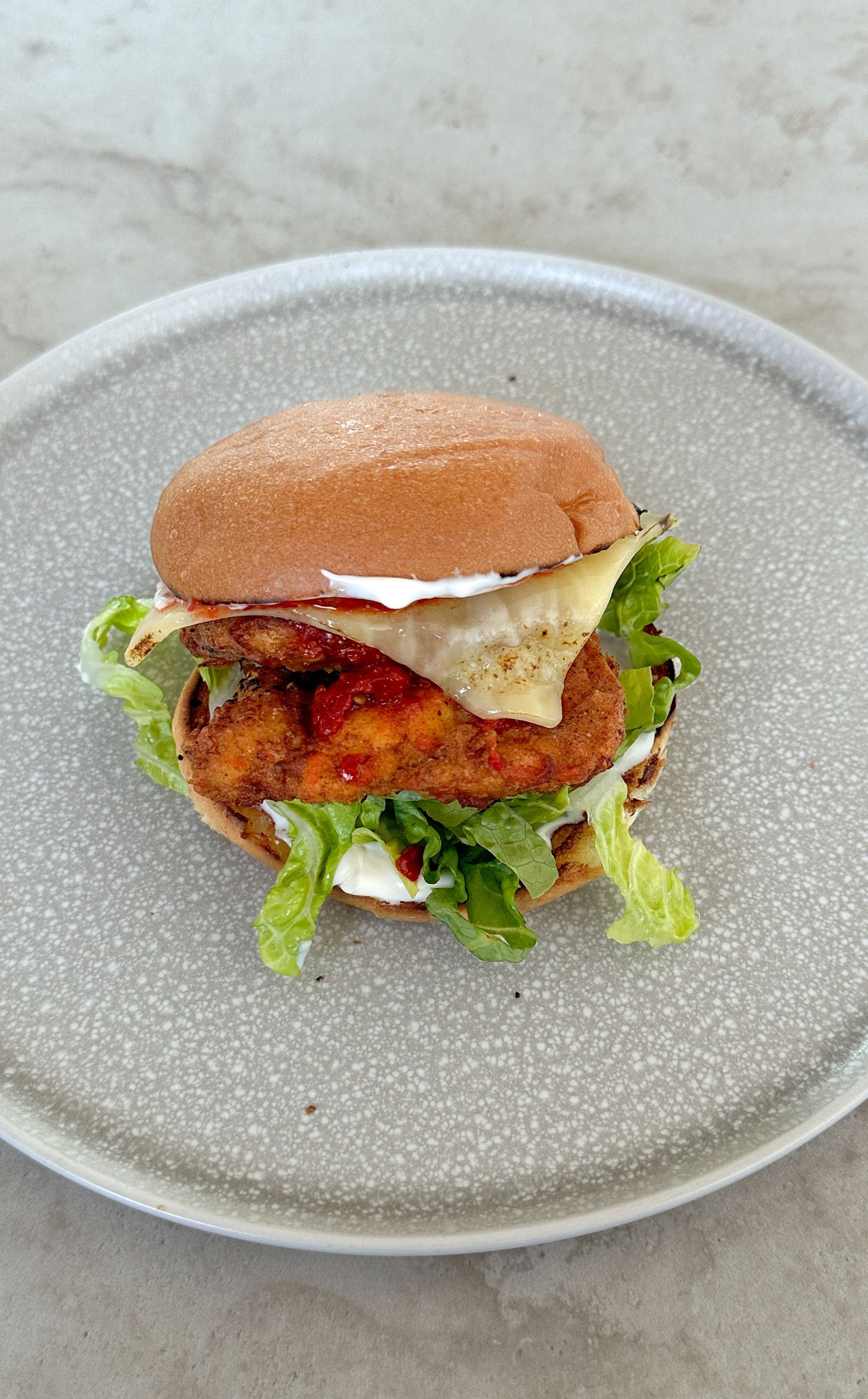 A close up of a hamburger on a plate on a table.