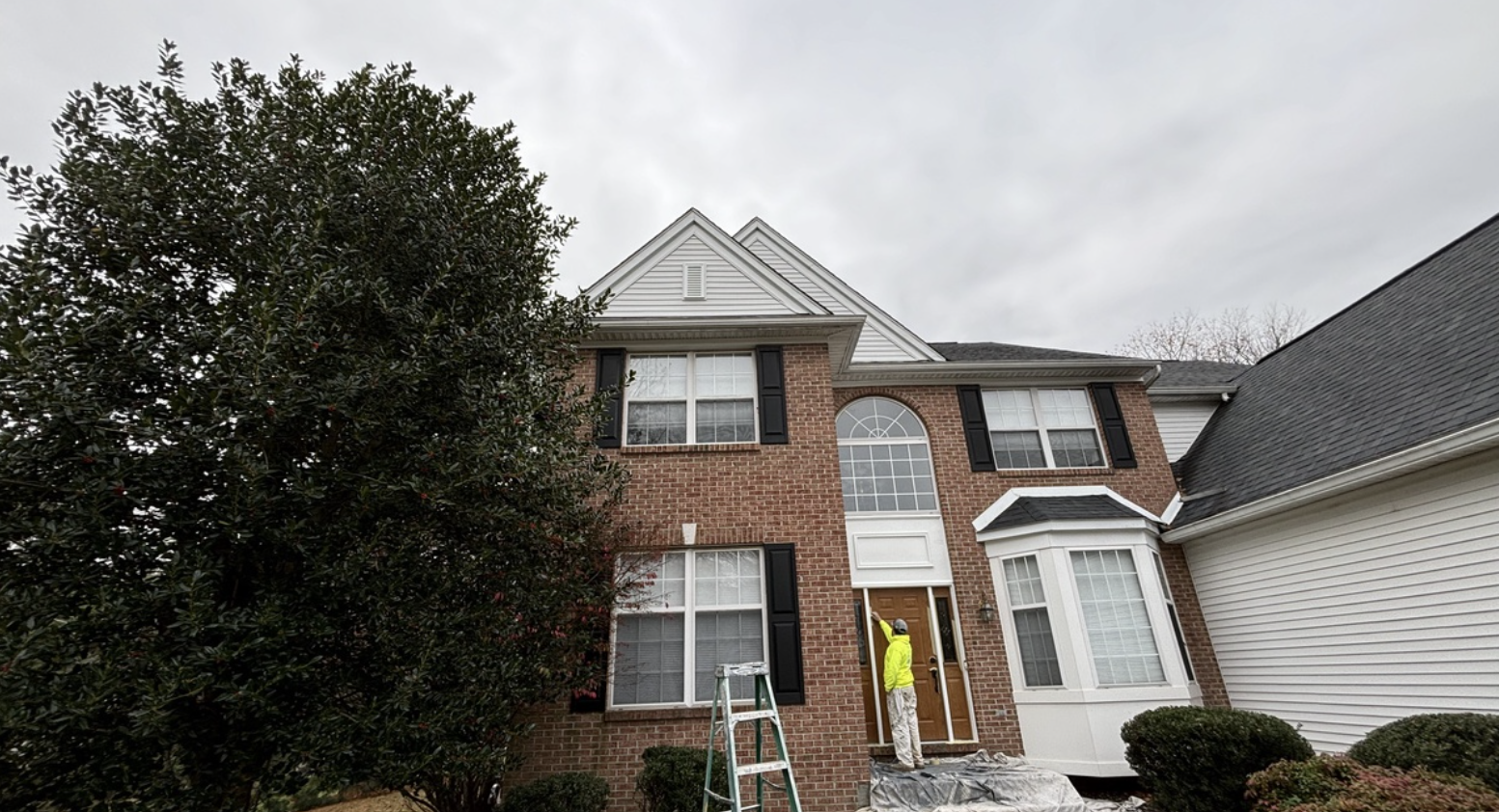 painter working on exterior of two story brick residence