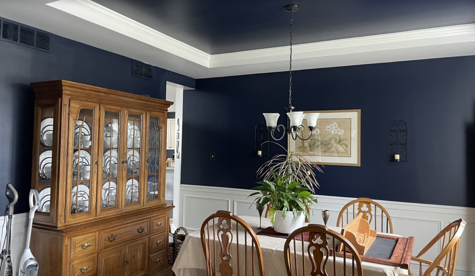 Dining room with beautiful dark blue painted wall and ceiling with white accents and trim.