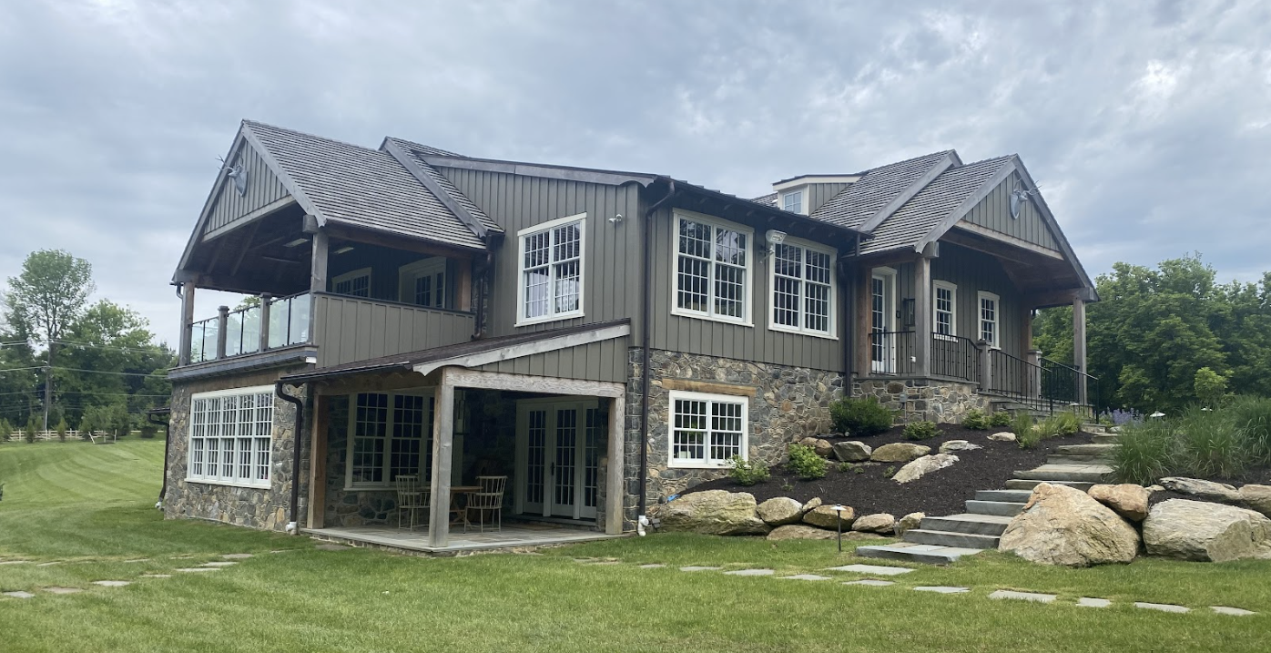 Side of a two story home with blue siding showing paint wear, indicating the need for a repaint. Tarp and ladder on the floor.