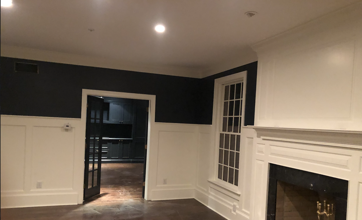 Side of a two story home with blue siding showing paint wear, indicating the need for a repaint. Tarp and ladder on the floor.