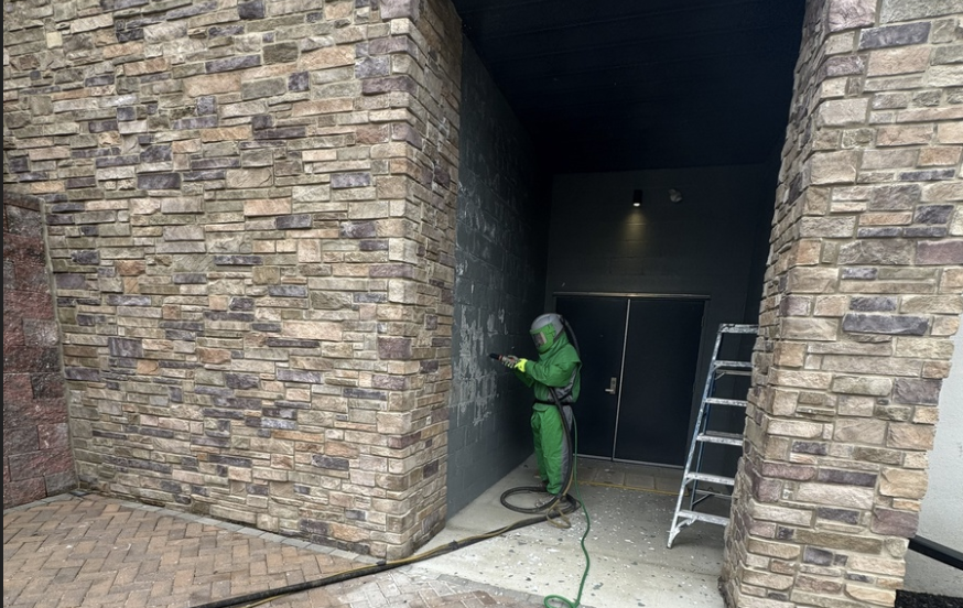 Interior of a home's living room with floor to ceiling glass windows, hardwood flooring, fireplace and blue walls