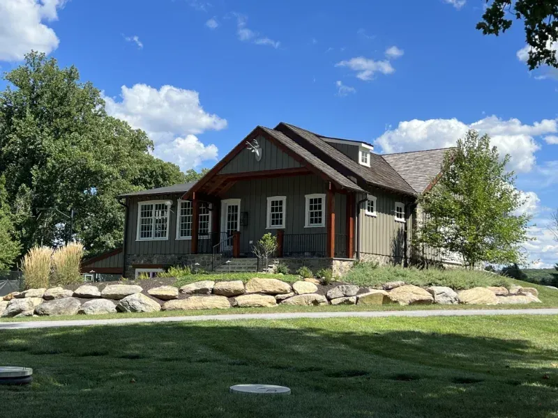 A large house is sitting on top of a lush green hill.