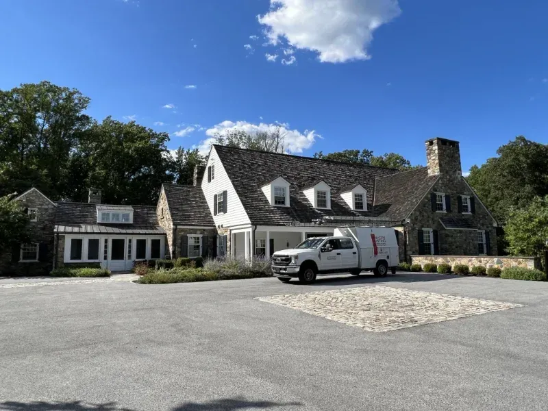 A white truck is parked in front of a large house