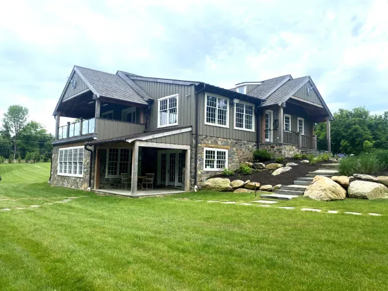 A large house with a lot of windows is sitting on top of a lush green field.