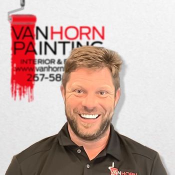 A man stands in front of a van horn painting logo