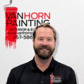 A man stands in front of a van horn painting logo