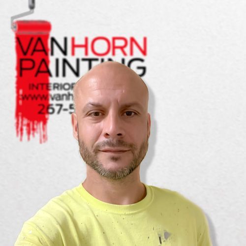 A bald man is standing in front of a van horn painting logo