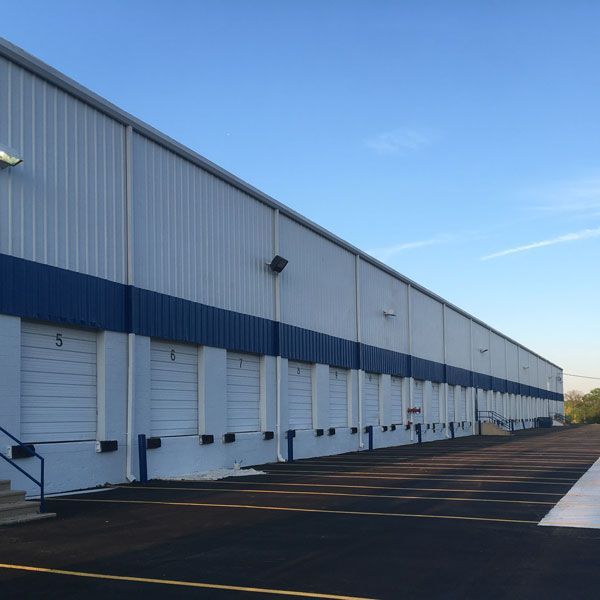 A large white building with blue trim has a parking lot in front of it