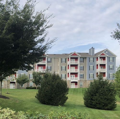 A large apartment building with a lush green lawn in front of it