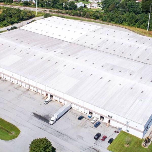 An aerial view of a large white building with trucks parked in front of it