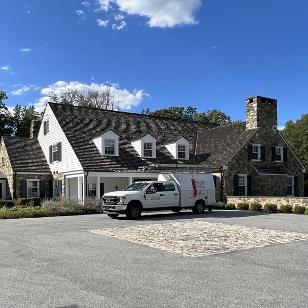 A white truck is parked in front of a large house