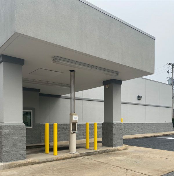 A gray building with yellow poles in front of it