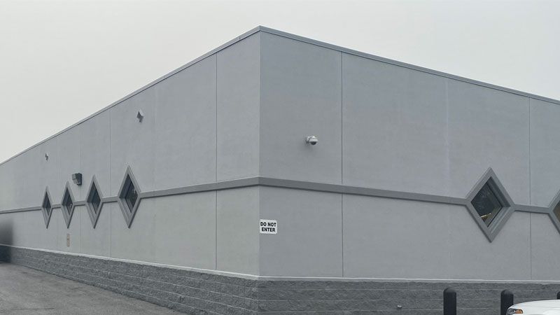 A large gray building with a lot of windows and a white truck parked in front of it.