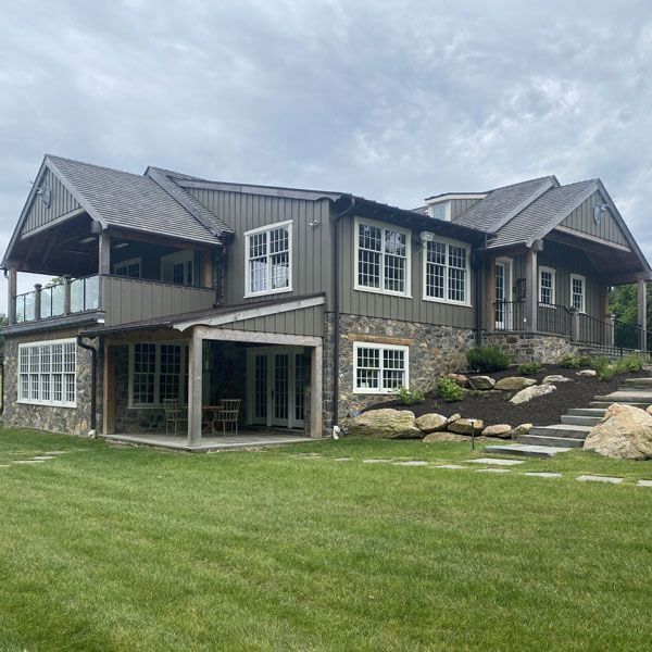 A large house with a lot of windows is sitting on top of a lush green hillside.