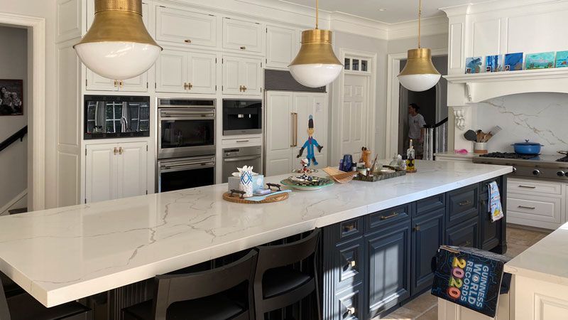 A kitchen with a large island and white counter tops.