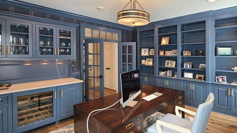 A home office with a desk , chair , computer and shelves.