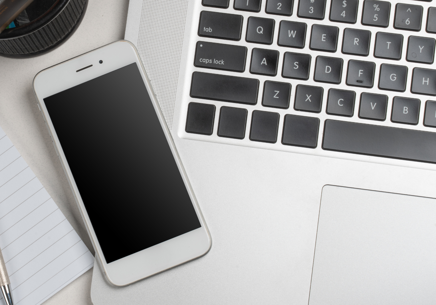 A cell phone is sitting next to a laptop on a desk