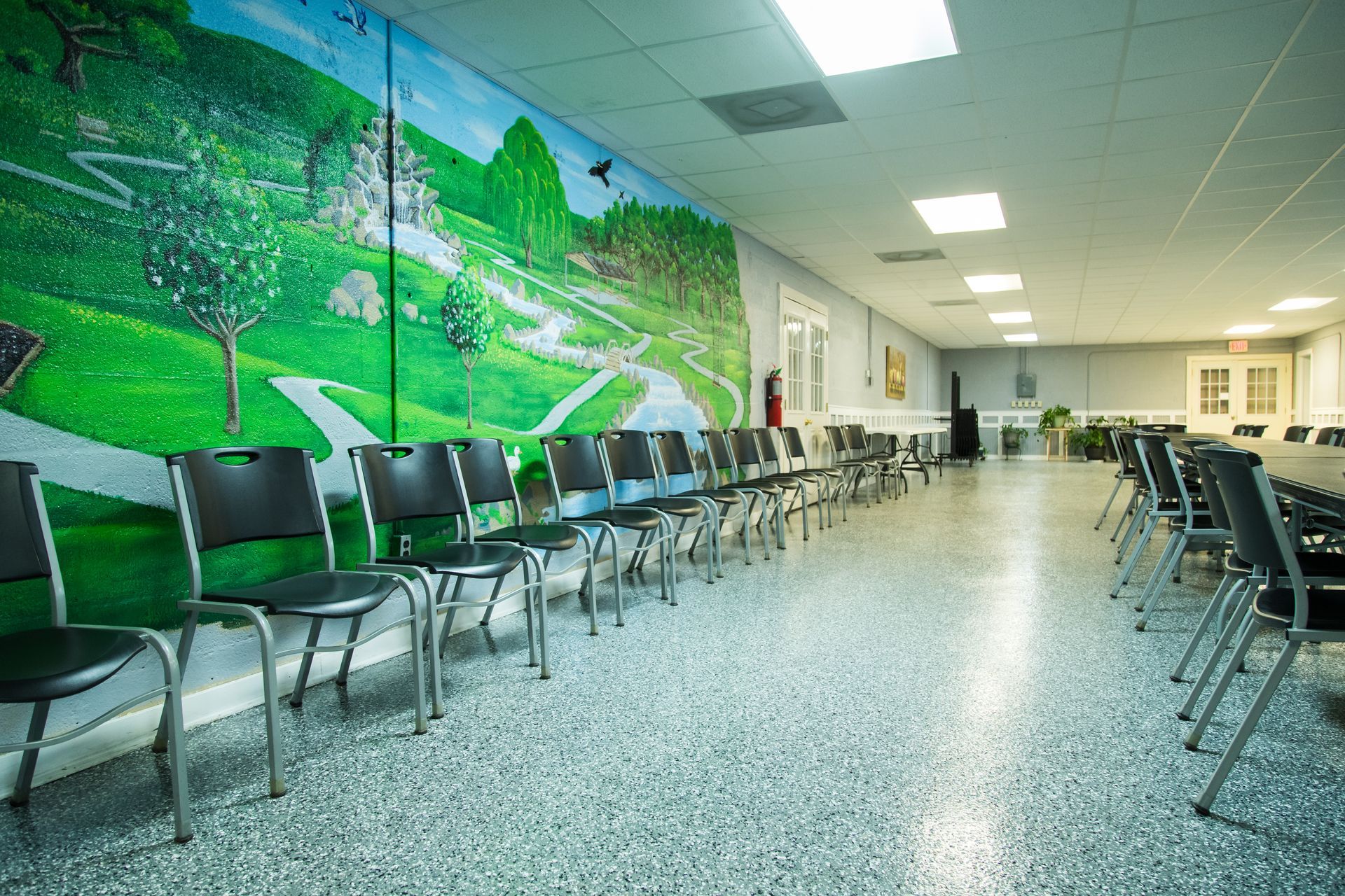 Empty hallway with rows of chairs and a green mural on the wall