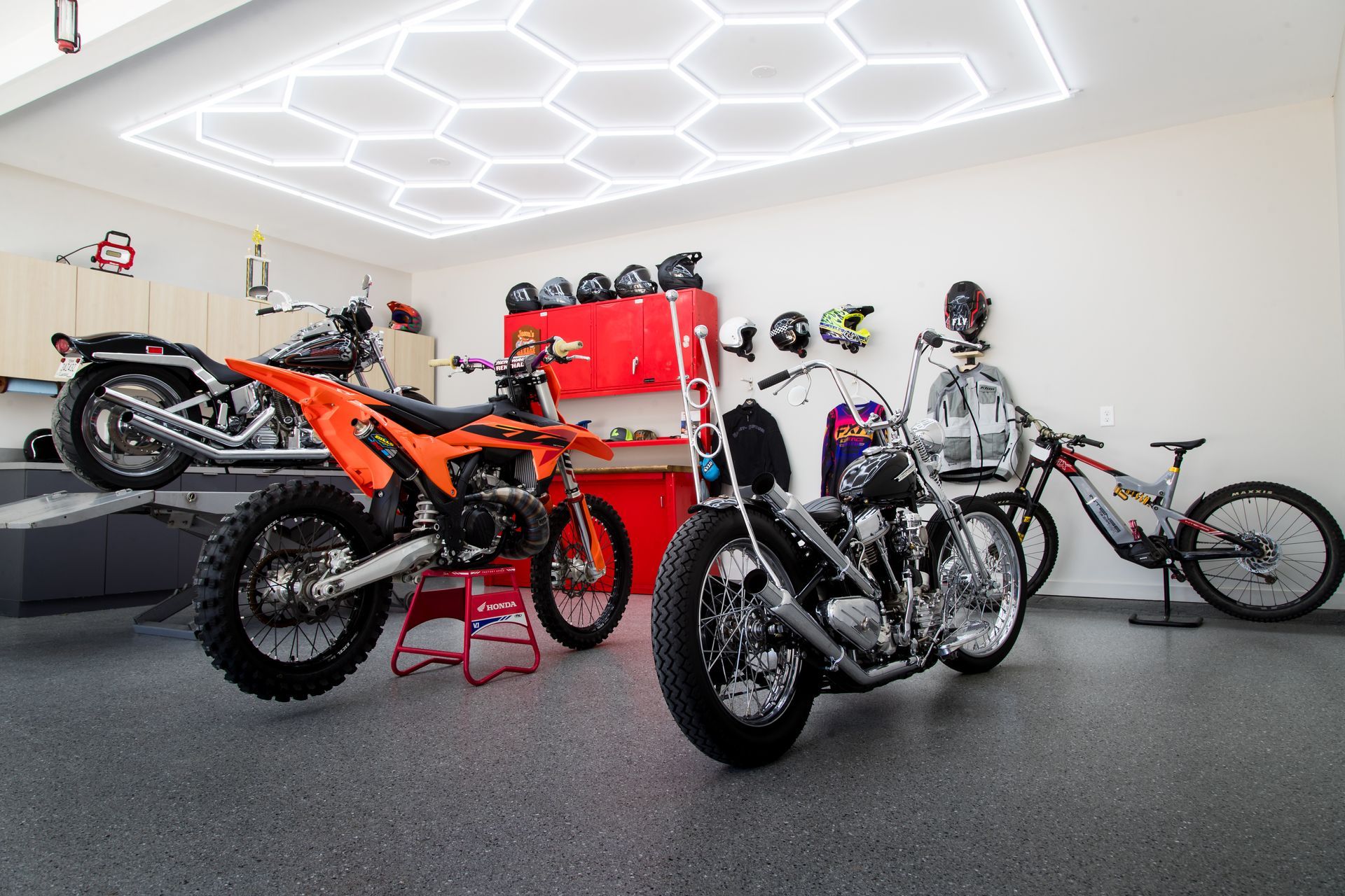 Motorcycles displayed in a bright modern garage with hexagonal ceiling lights