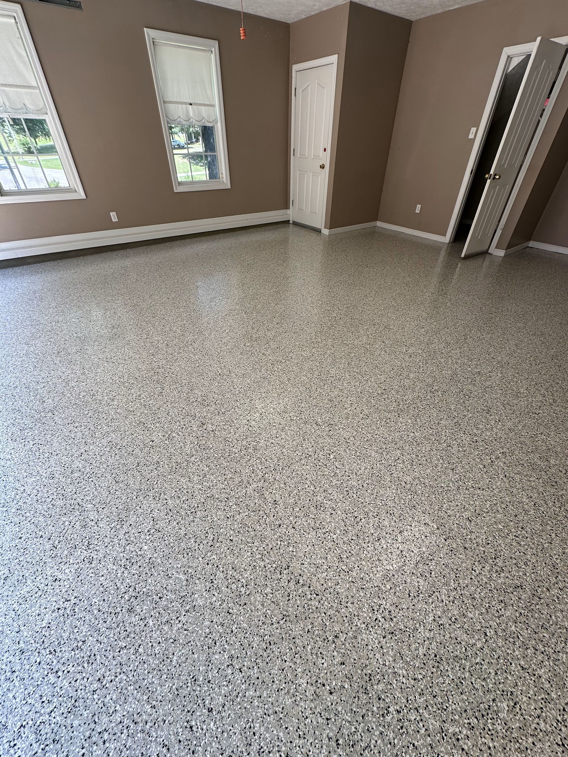 A large room with a concrete floor and two windows.
