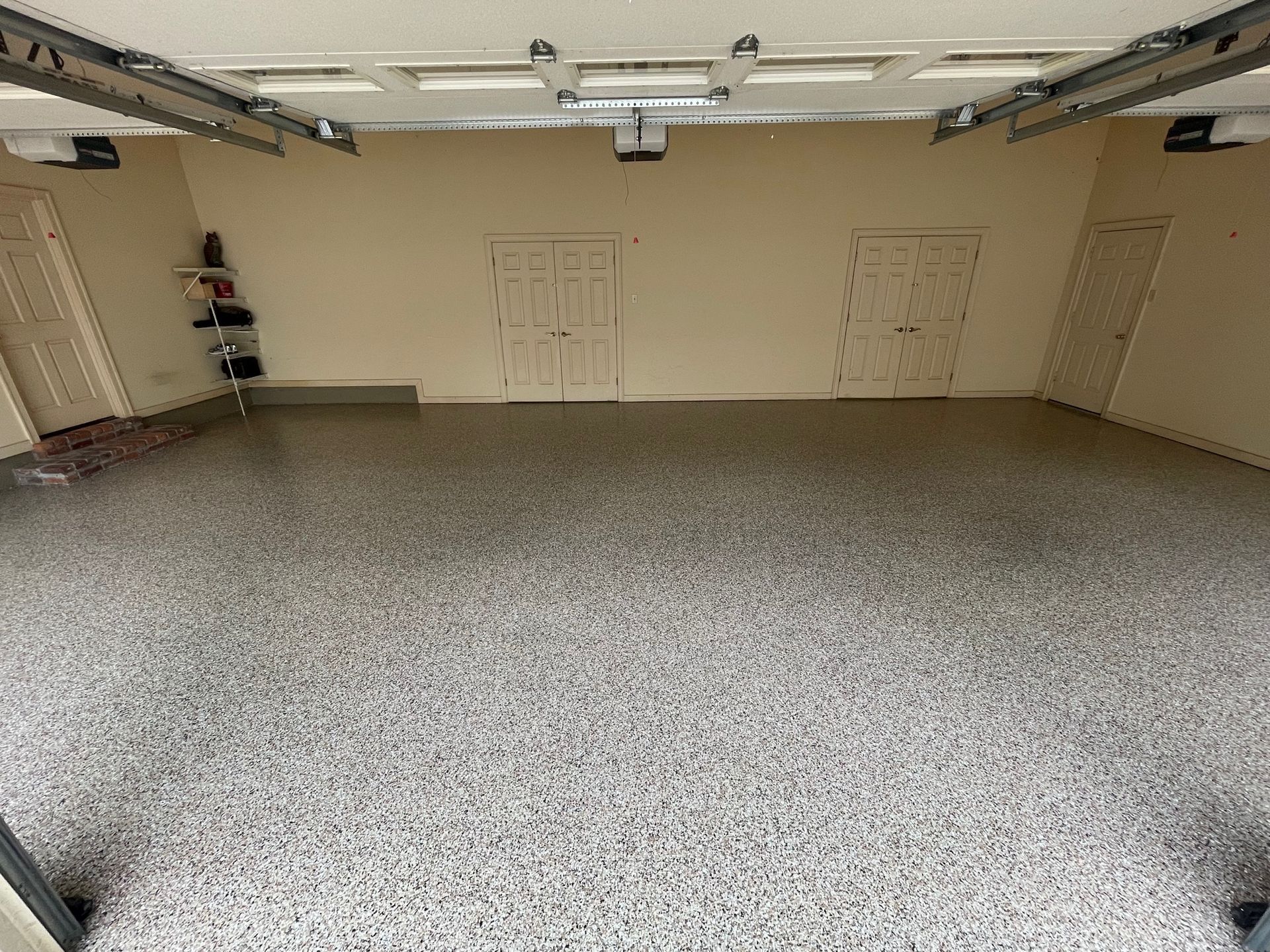 A garage with a concrete floor and a garage door open.