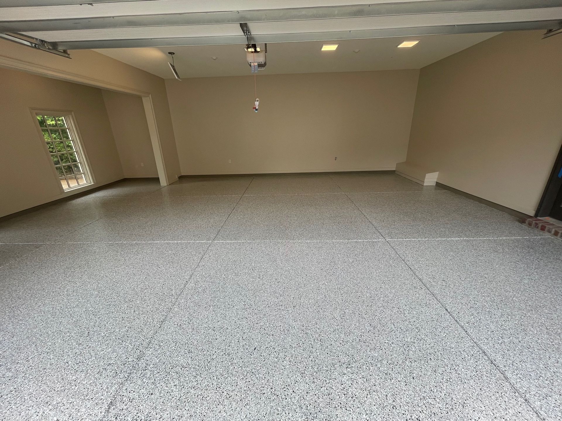 A garage with a gray floor and a garage door open.