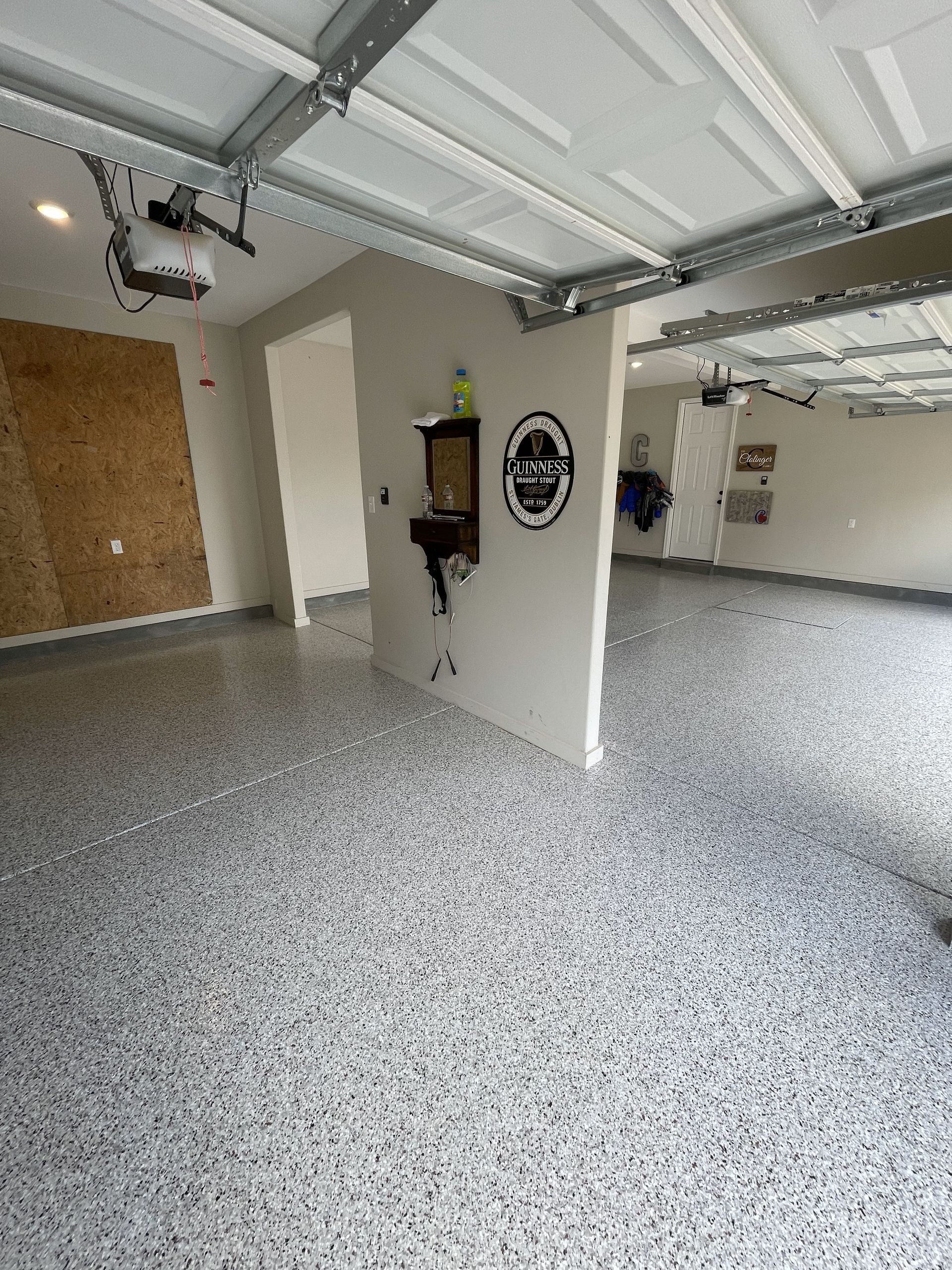 A garage with a concrete floor and a garage door open.