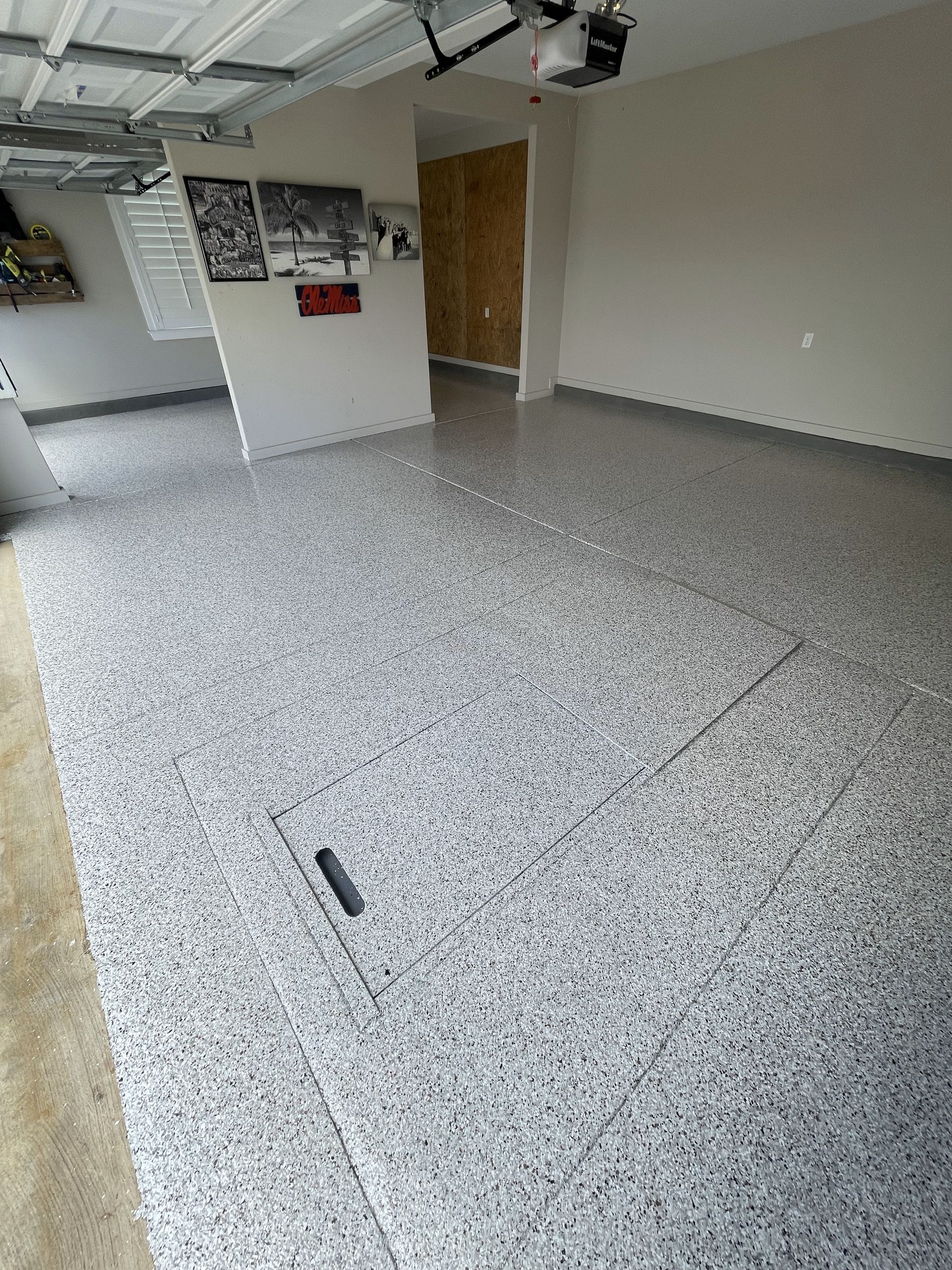 A garage with a gray floor and a garage door open.
