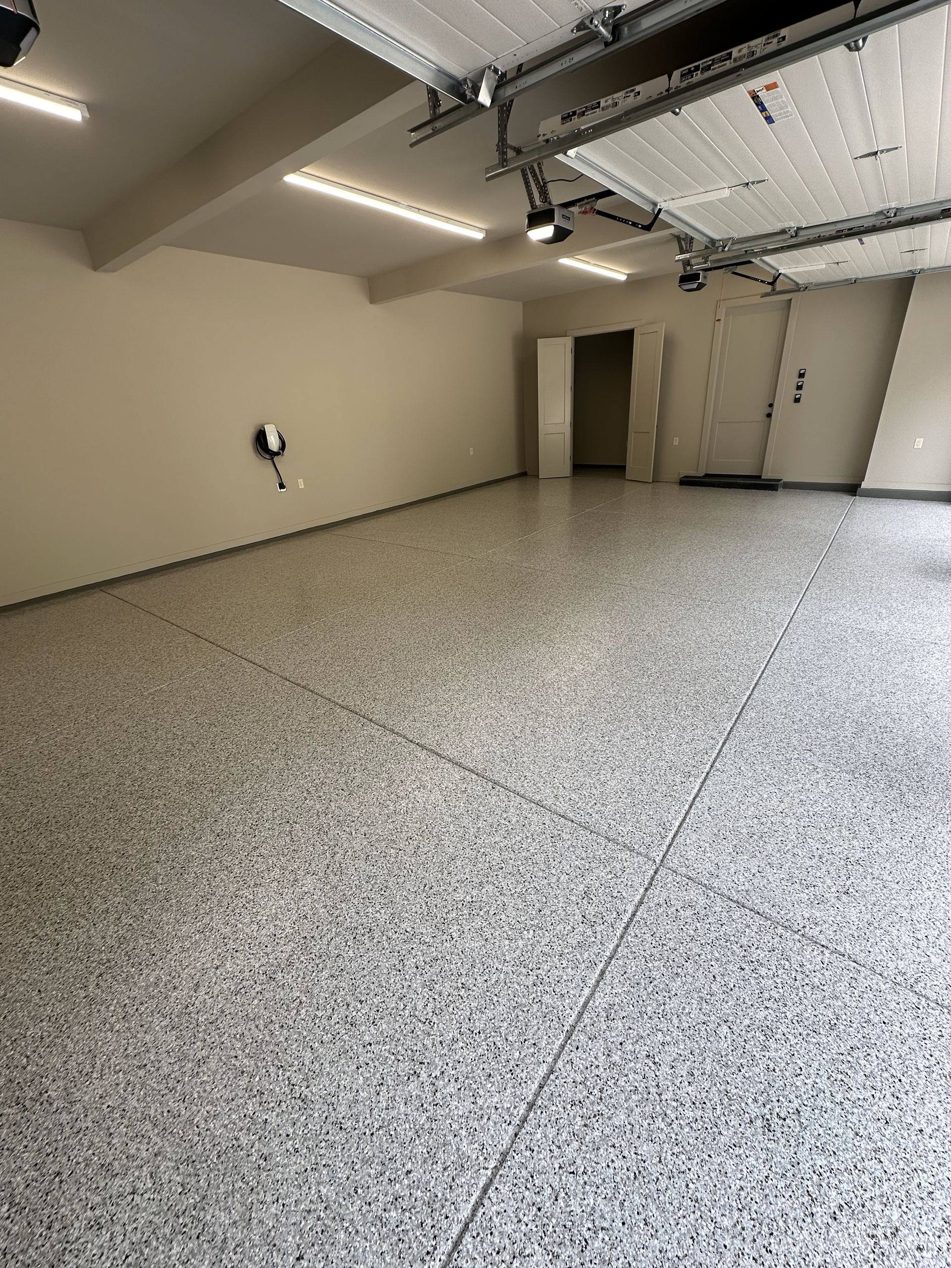 An empty garage with a garage door open and a gray floor.